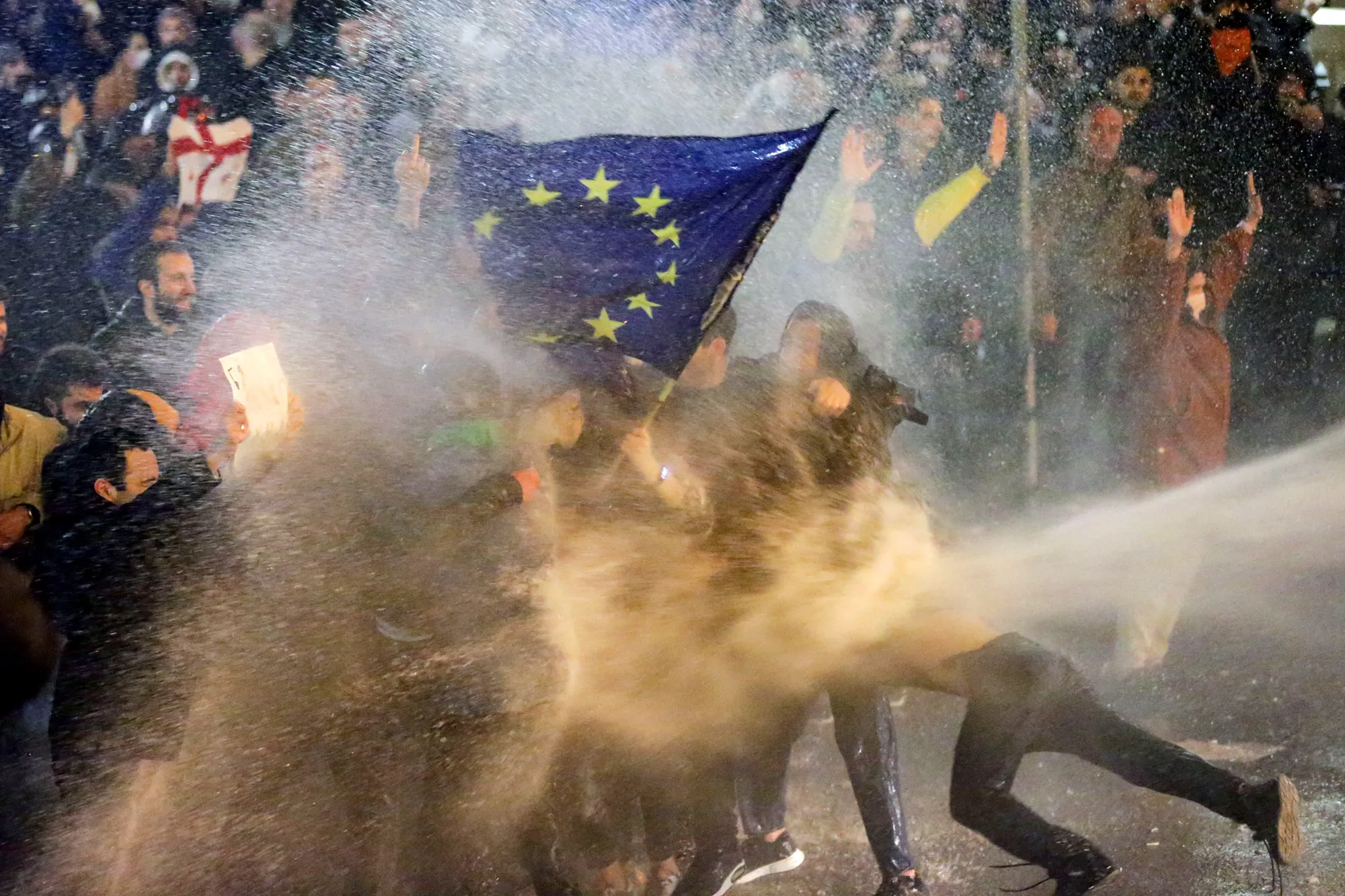 A protester is forced to the ground by water cannon during clashes between riot police and demonstrators.