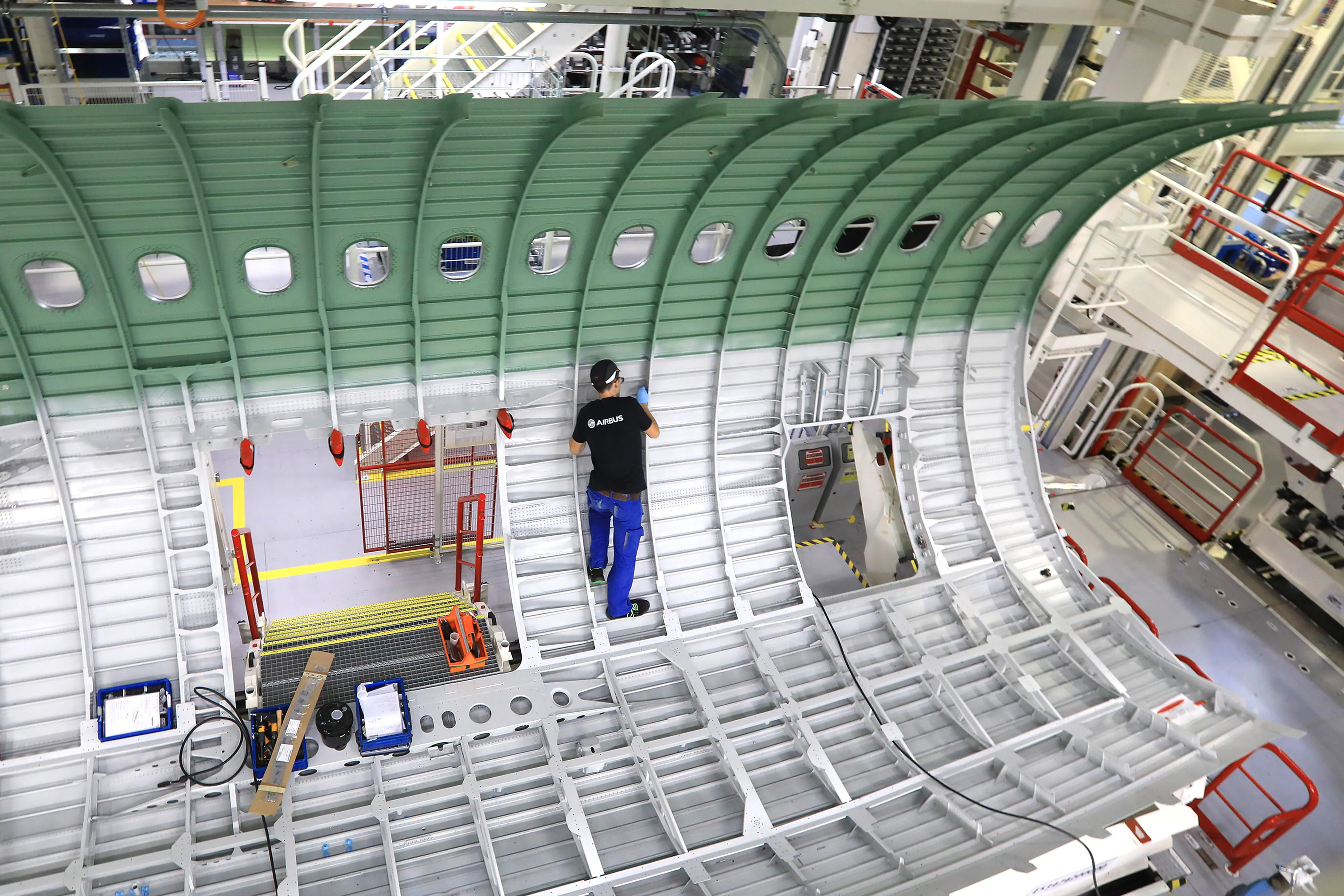 An employee works on a center fuselage section of an Airbus A320 passenger aircraft inside the new Airbus SE A320 family assembly line hangar in Hamburg.