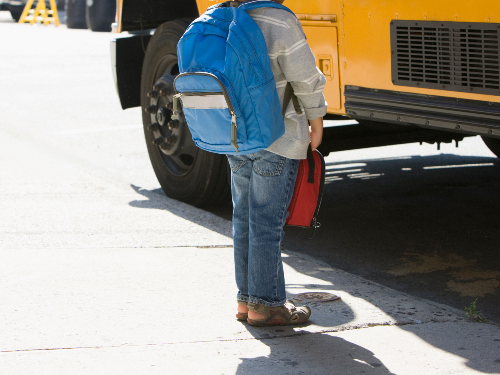 Mixed race boy standing near school bus