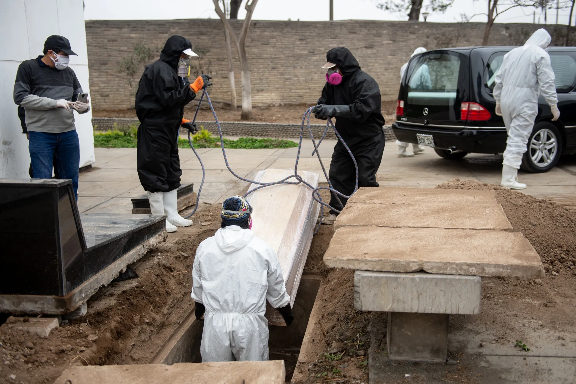 Workers lower the casket of a Covid-19 victim at a cemetery in Lima, Peru, on June 3.