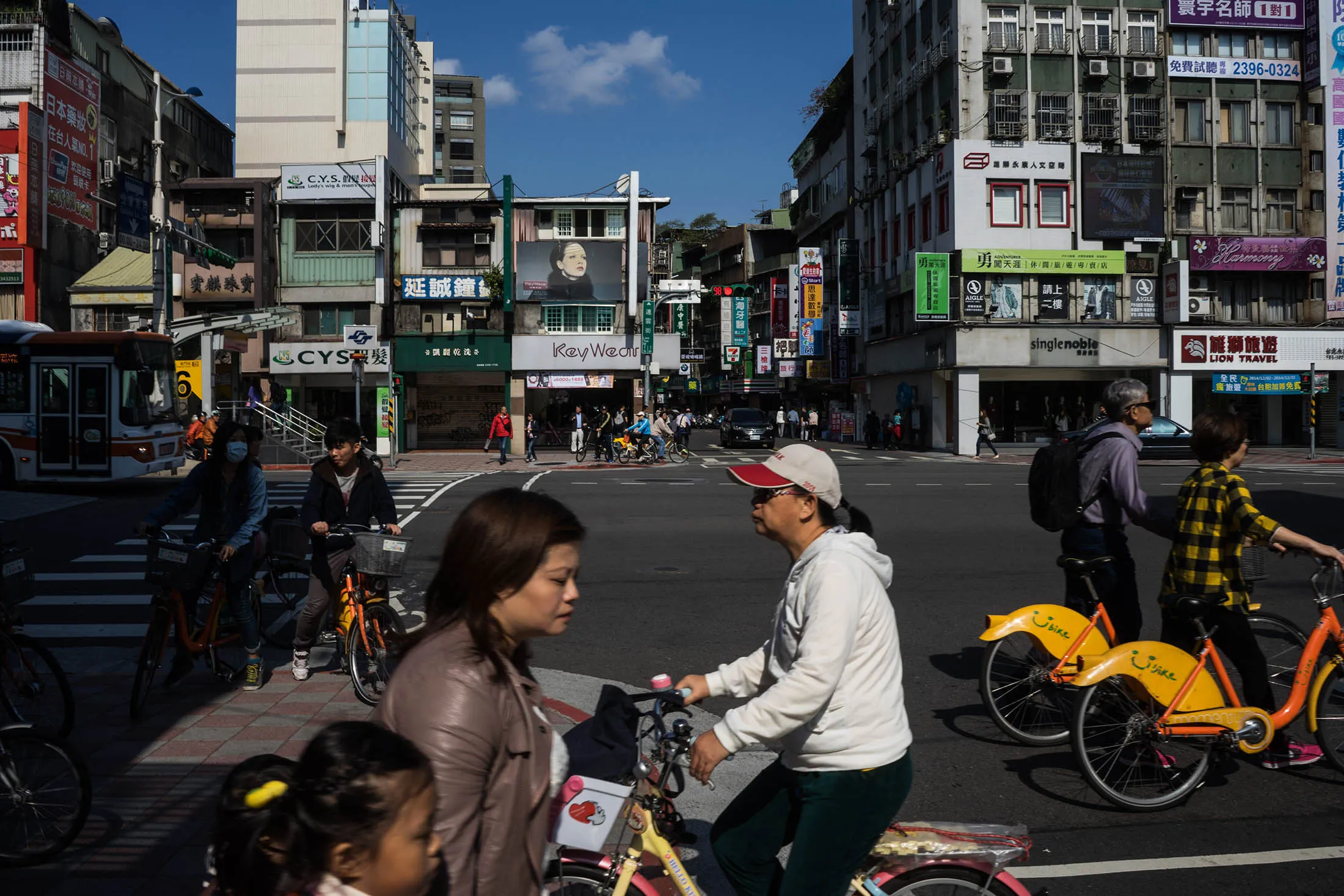 Cyclists cross a road near stores along Yongkang Street in Taipei.
