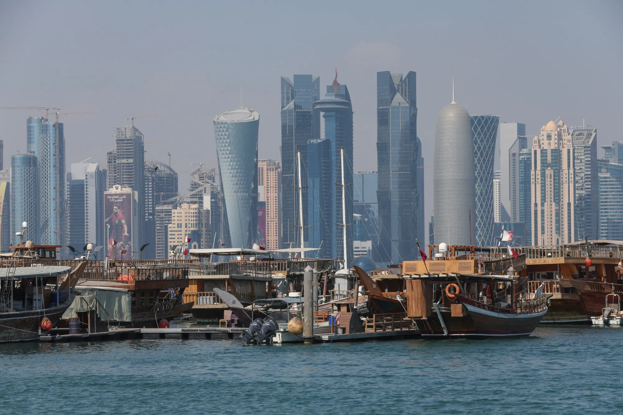 Commercial skyscrapers of the Qatar Financial Centre on the skyline beyond traditional dhow boats in Doha.