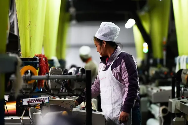 A Chinese worker sews clothes at a garment factory in Zouping county, Shandong province, on Nov. 16