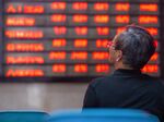 An investor looks at screens showing stock market movements at a securities company in Nanjing.