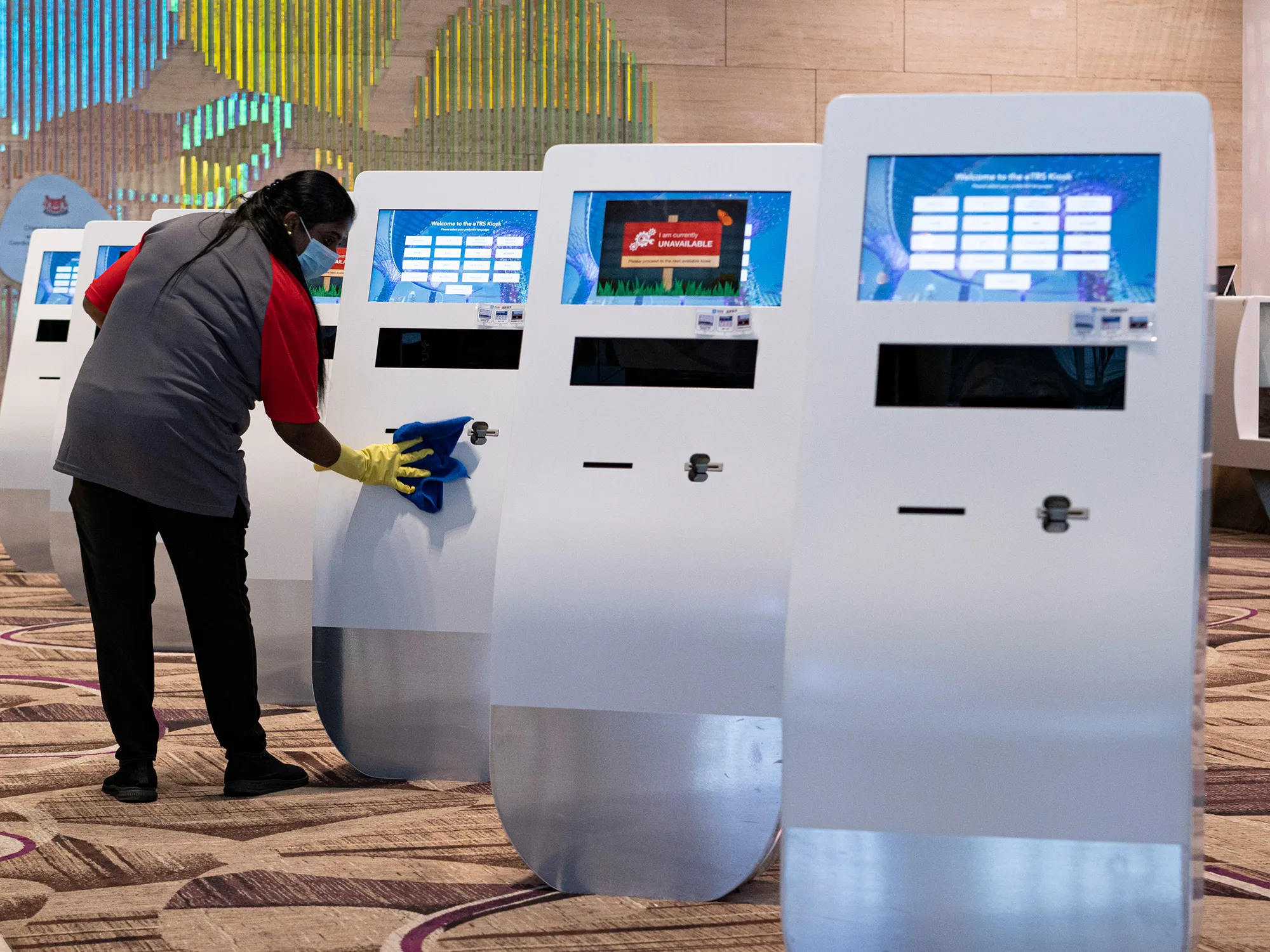 An employee wearing a face mask&nbsp;cleans a kiosk at the departure hall of Singapore Changi Airport.