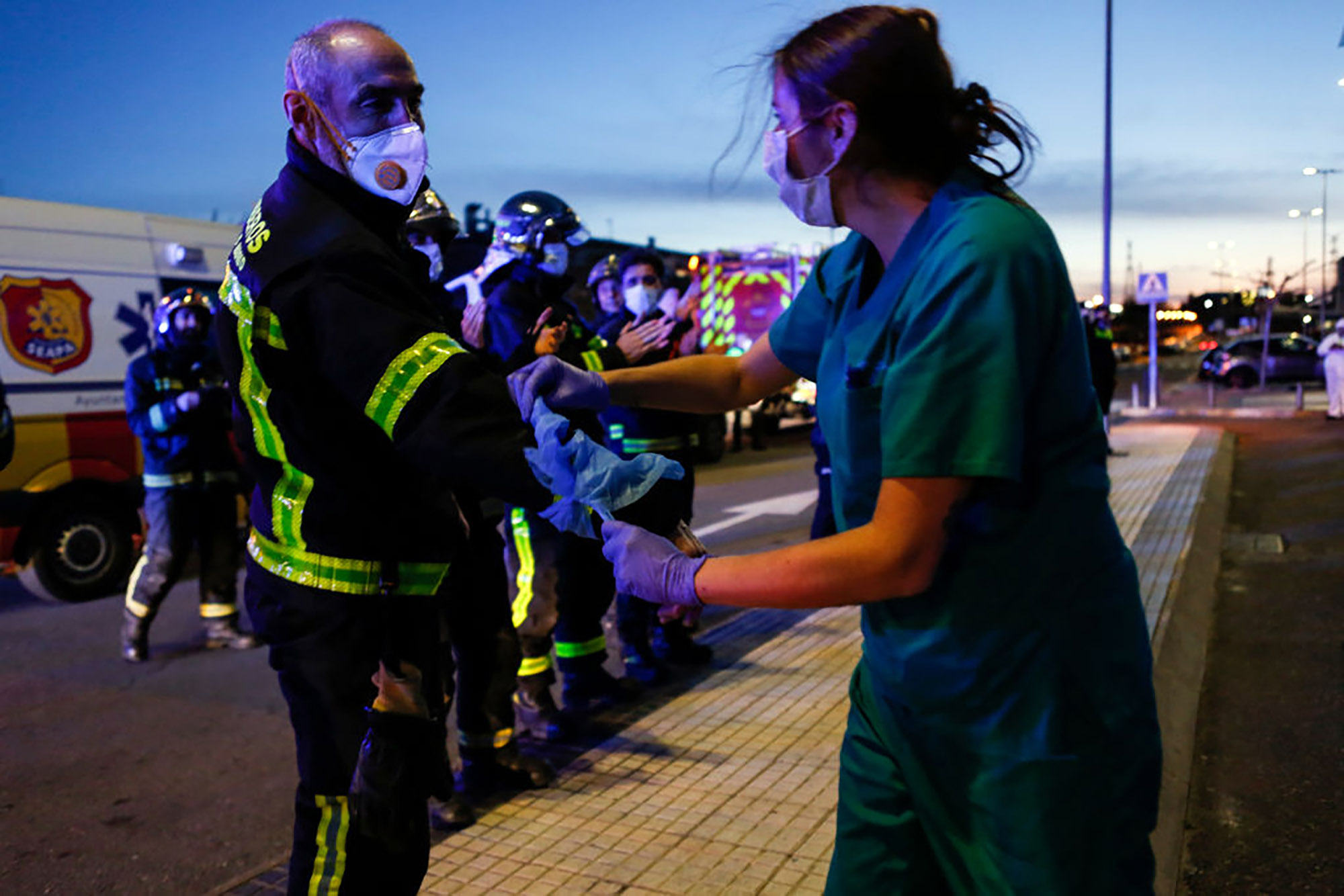 A sanitation worker ties a protective coat to the arm of a fireman as a symbol of gratitude&nbsp;for their support during Covid-19 crisis, in Madrid,, on March 28.