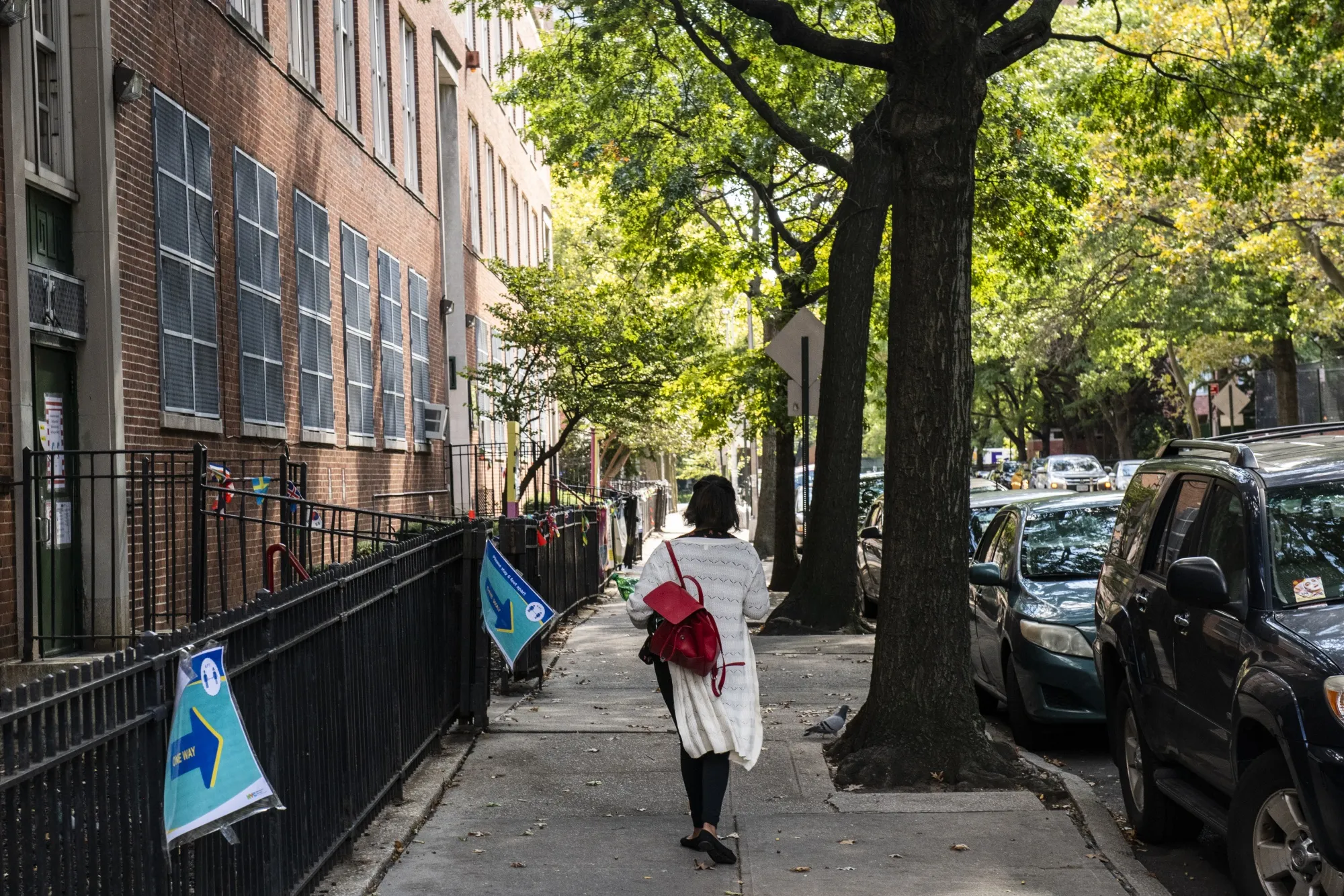 A pedestrian passes in front of a public school in the Rego Park neighborhood of New York City.