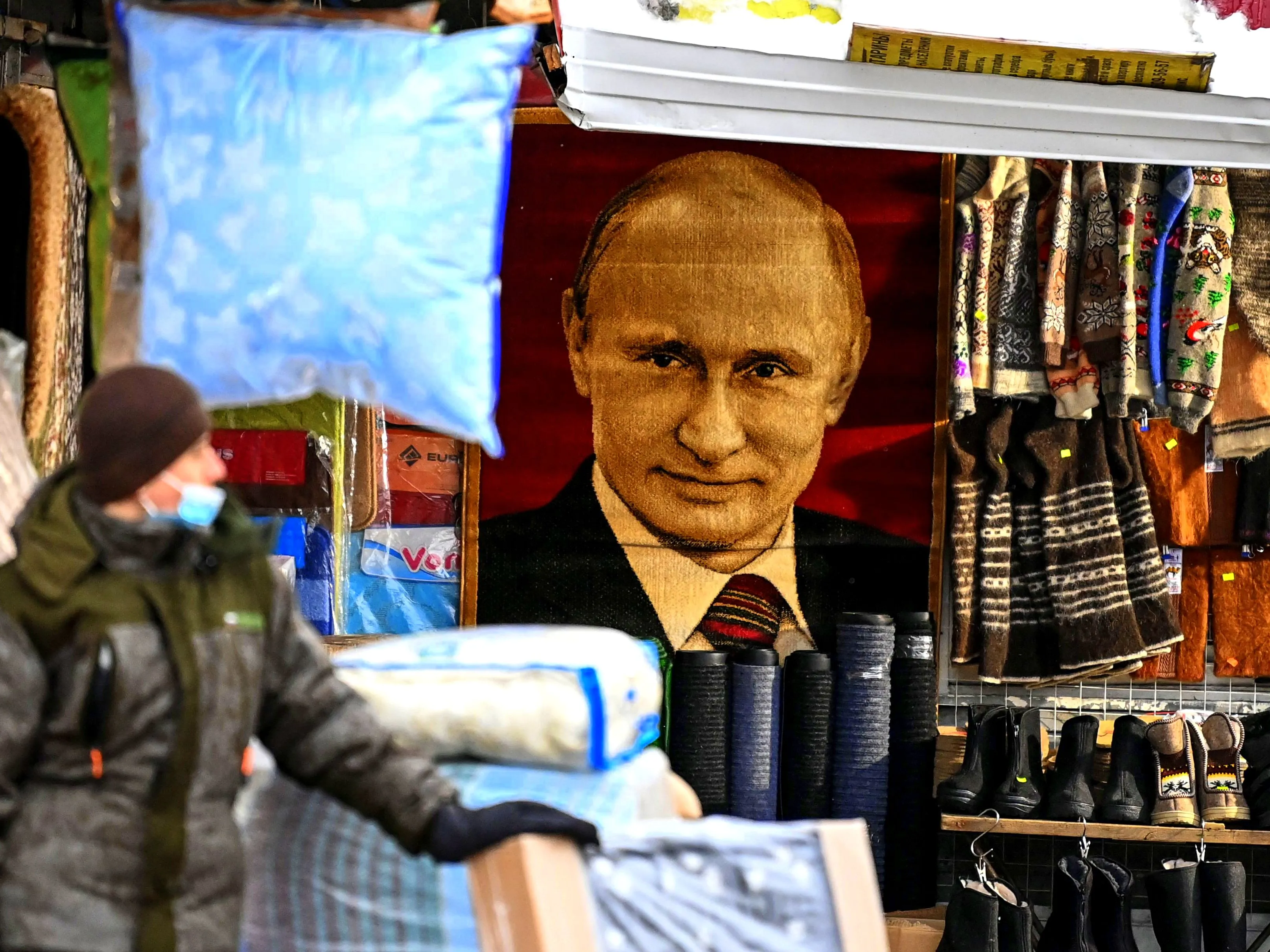 A vendor stands in front of a carpet with a portrait of Russian President Vladimir Putin at a market in Moscow.&nbsp;