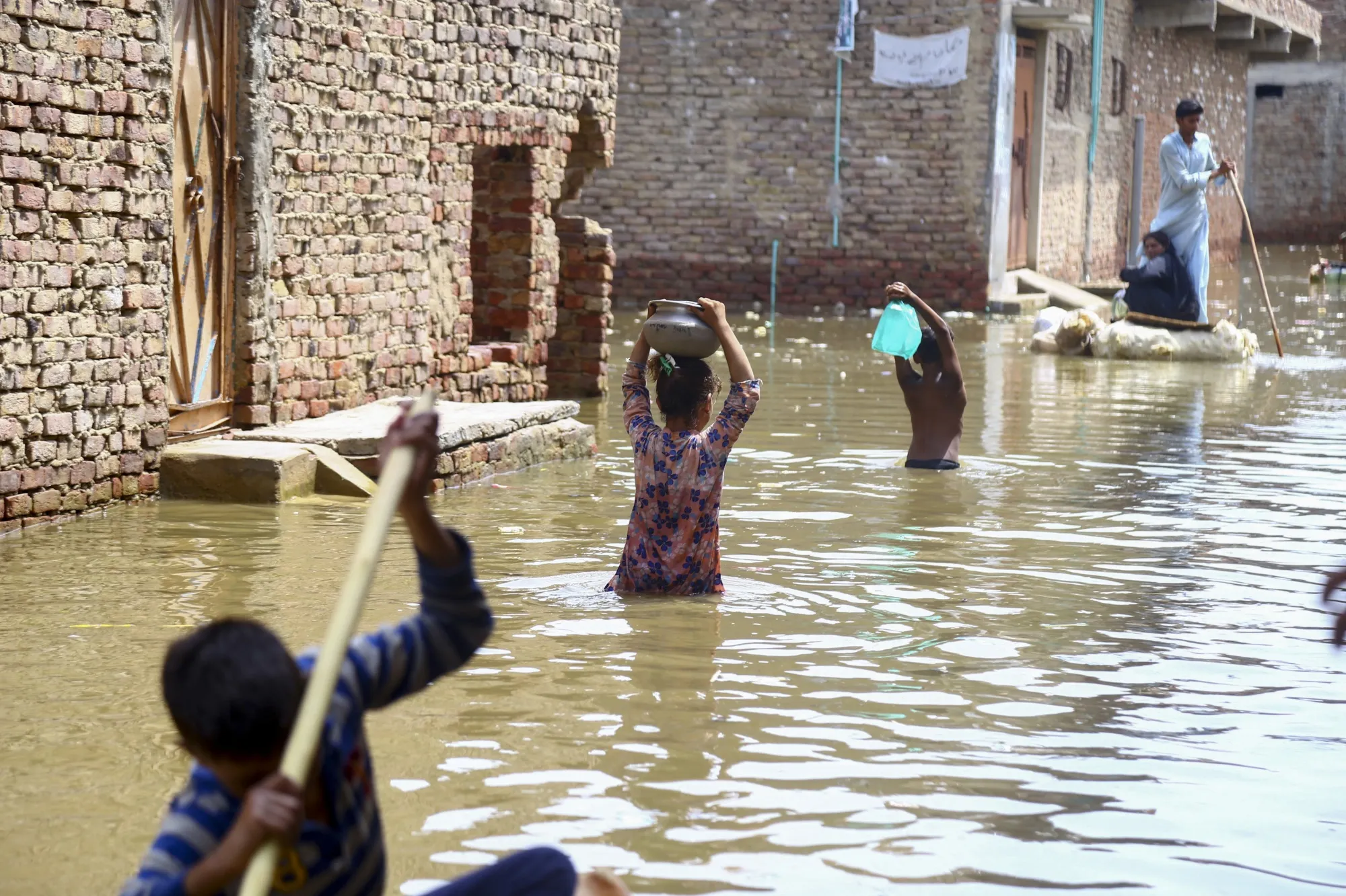 People wade through floodwater in a residential area following heavy monsoon rains in Hyderabad, Pakistan, on Aug. 26, 2025.