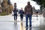 Reggie Brown, of Centralia, carries his daughter, Ocean, 4, on his shoulders as he walks through the floodwaters on Highway 507 with his wife, Jonell Brown, on Friday, Jan. 7, 2022, in Centralia, Wash. The highway had flooded after heavy rains caused the Skookumchuck River to rise about its northern banks.(Peter Caster/The News Tribune via AP)