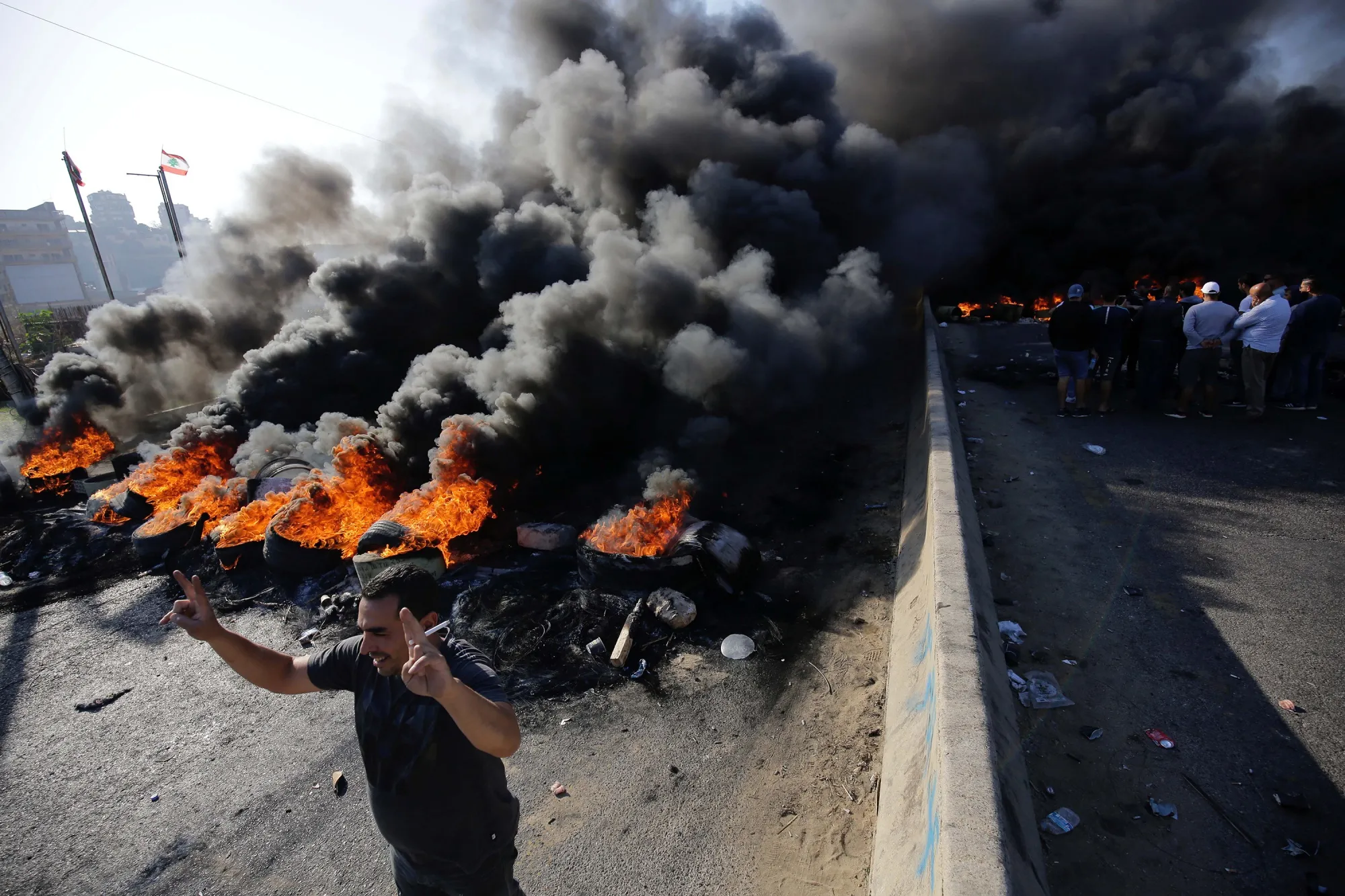 An anti-government protester flashes the V-sign for victory in front of burning tyres in Tripoli on Nov. 13.