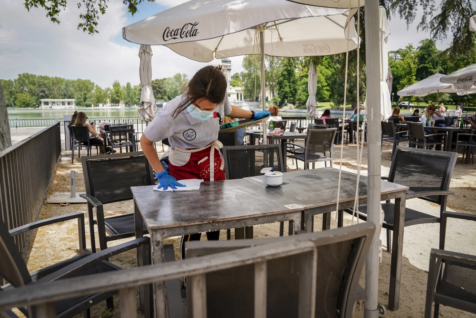 A waitress sanitizes a table surface at the outdoor terrace of a cafe in Madrid, on May 25.