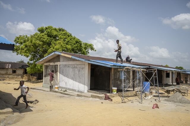 Salala's new owner started rebuilding dilapidated worker housing. Several people work on the roof and painting the exterior.