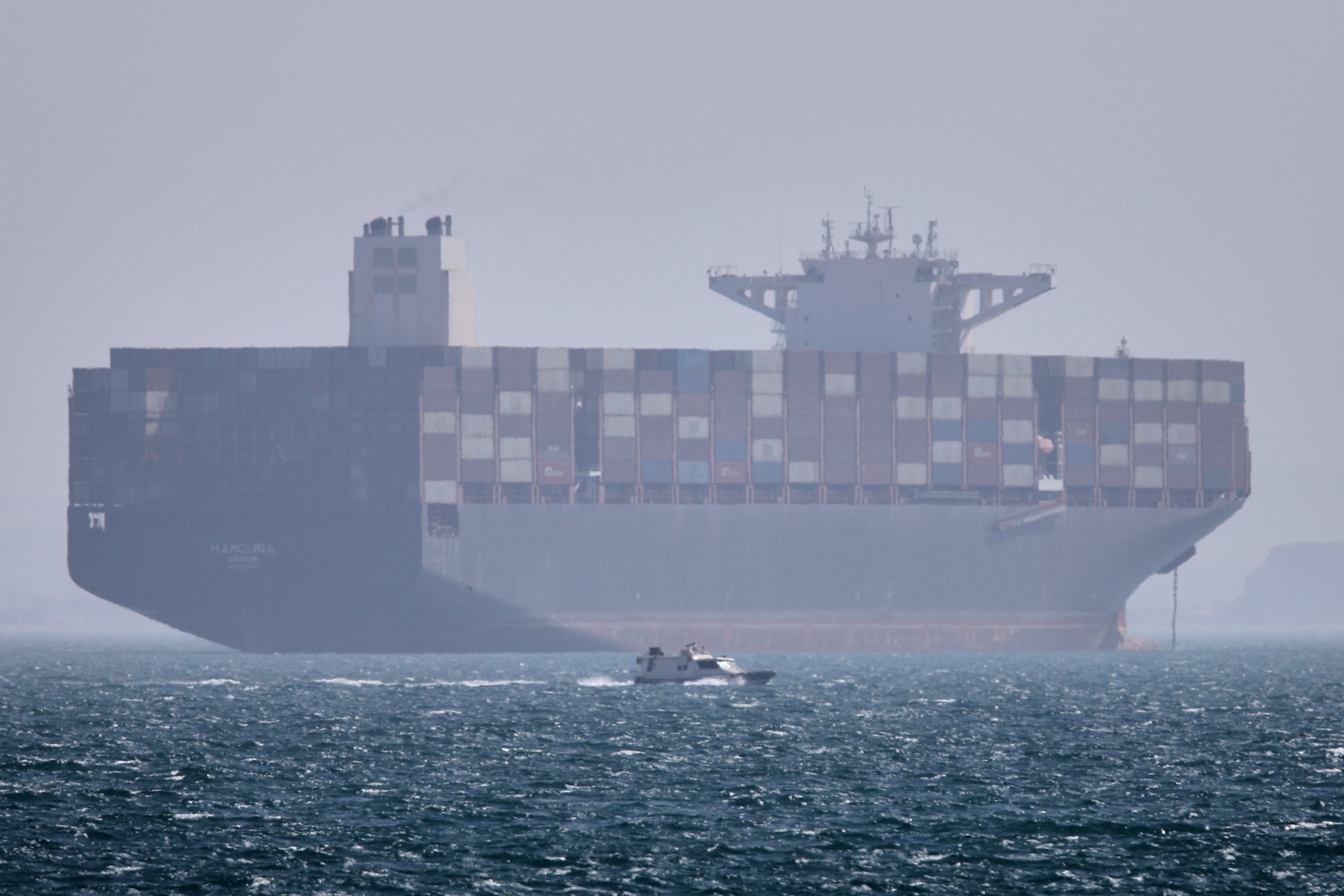 A container ship sits at anchor as a small motorboat passes in the foreground in the Strait of Hormuz off Bandar Abbas, Iran, Saturday, May 2, 2026. (Amirhosein Khorgooi/ISNA via AP) Photographer: Amirhosein Khorgooi/ISNA