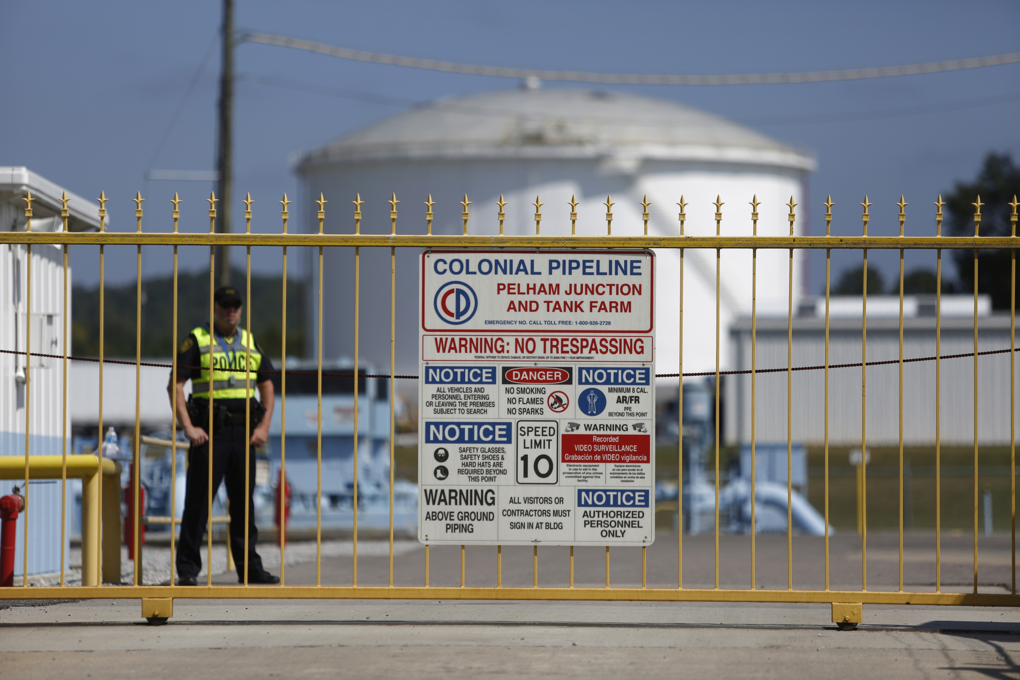 A police officer stands guard inside the gate to the Colonial Pipeline Co. Pelham junction and tank farm in Pelham, Alabama.