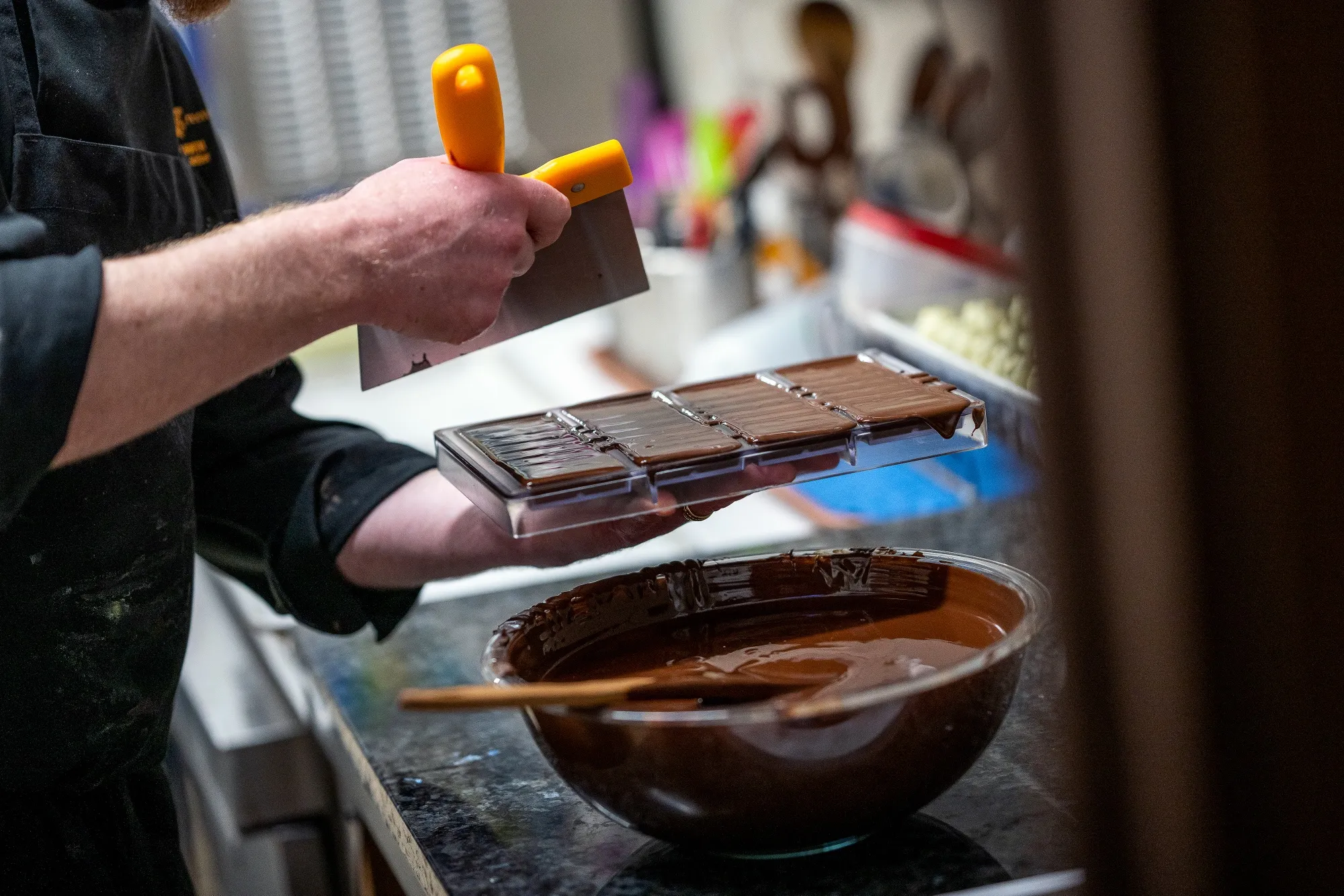 A worker scrapes chocolate from a mold at a confectionery store in Canada.