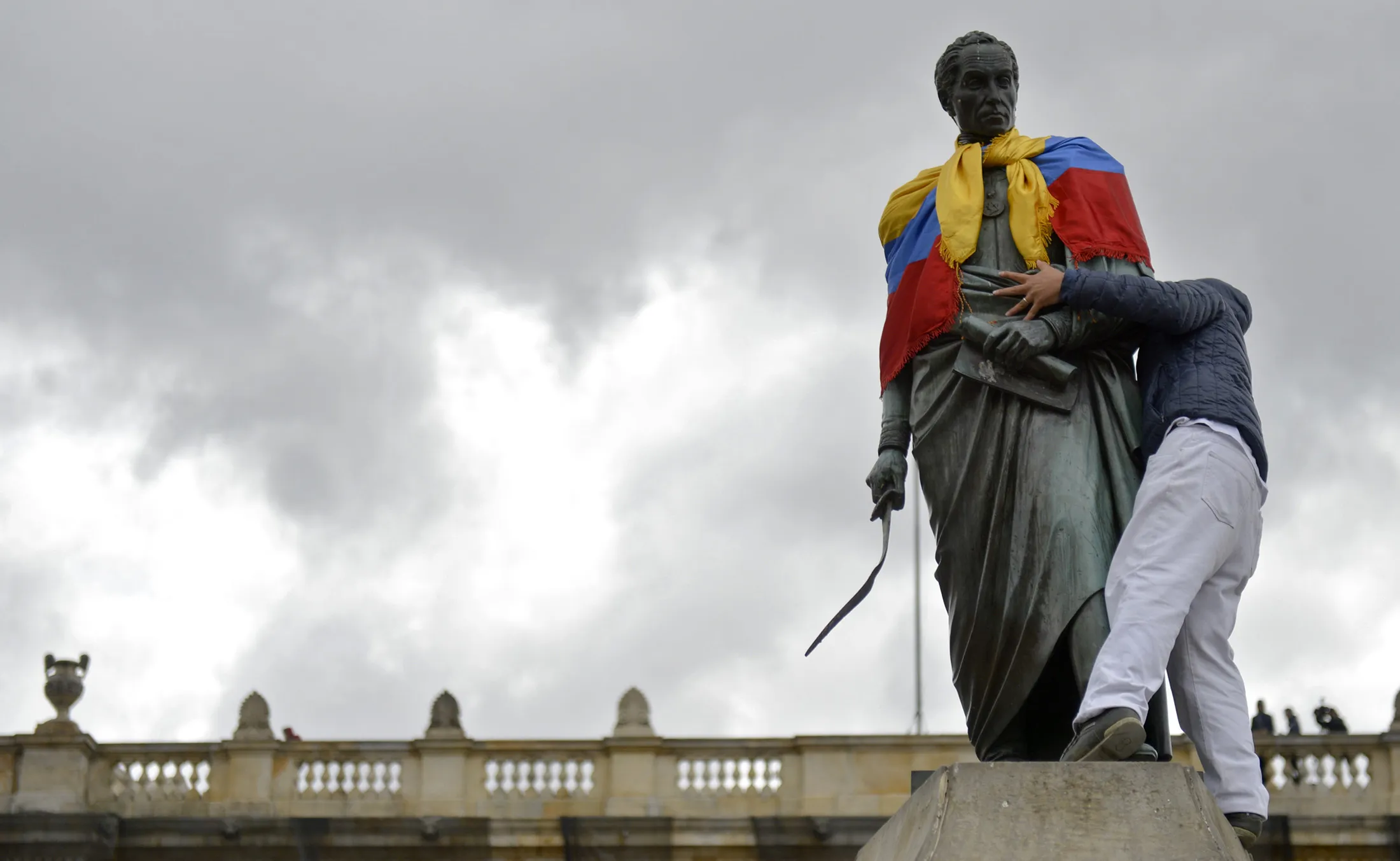 A demonstrator puts a Colombian flag on a monument during a march during a national strike in Bogota on Nov. 27.