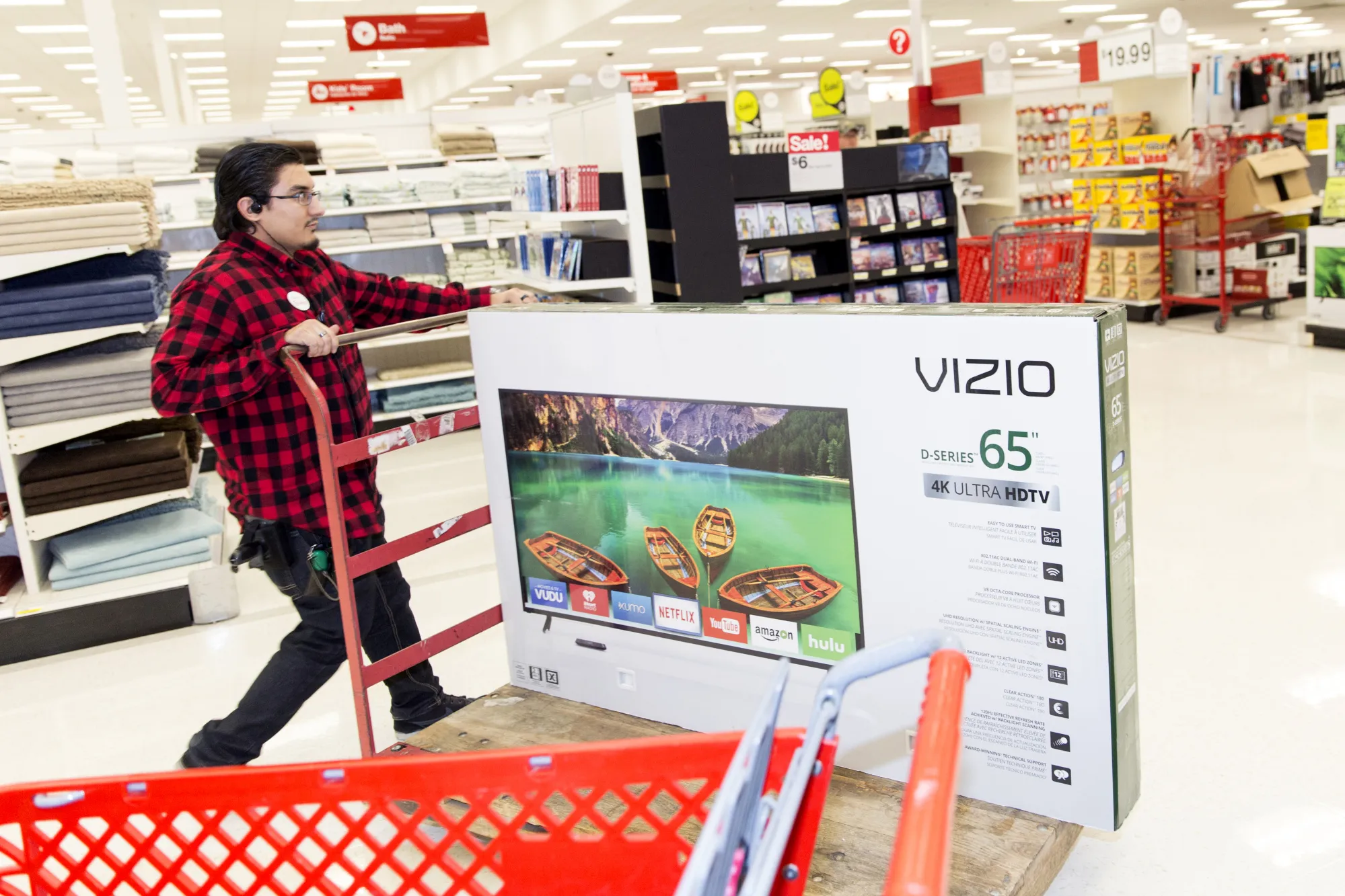 An employee pushes a trolley with a Vizio television at a store.