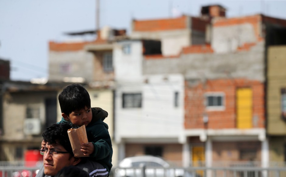 A man with a small boy on his shoulders walks through Villa 31, an informal settlement in Buenos Aires. 