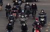 Chinese commuters, all wearing protective masks, ride bikes and scooters as they cross an intersection in rush hour in Beijing on Feb. 24.