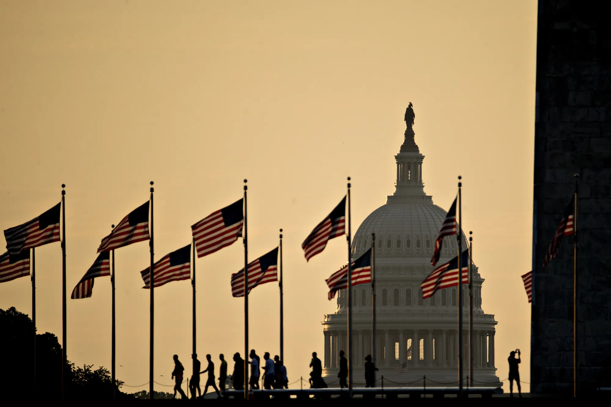 The U.S. Capitol building stands past visitors at the Washington Monument in Washington, D.C.