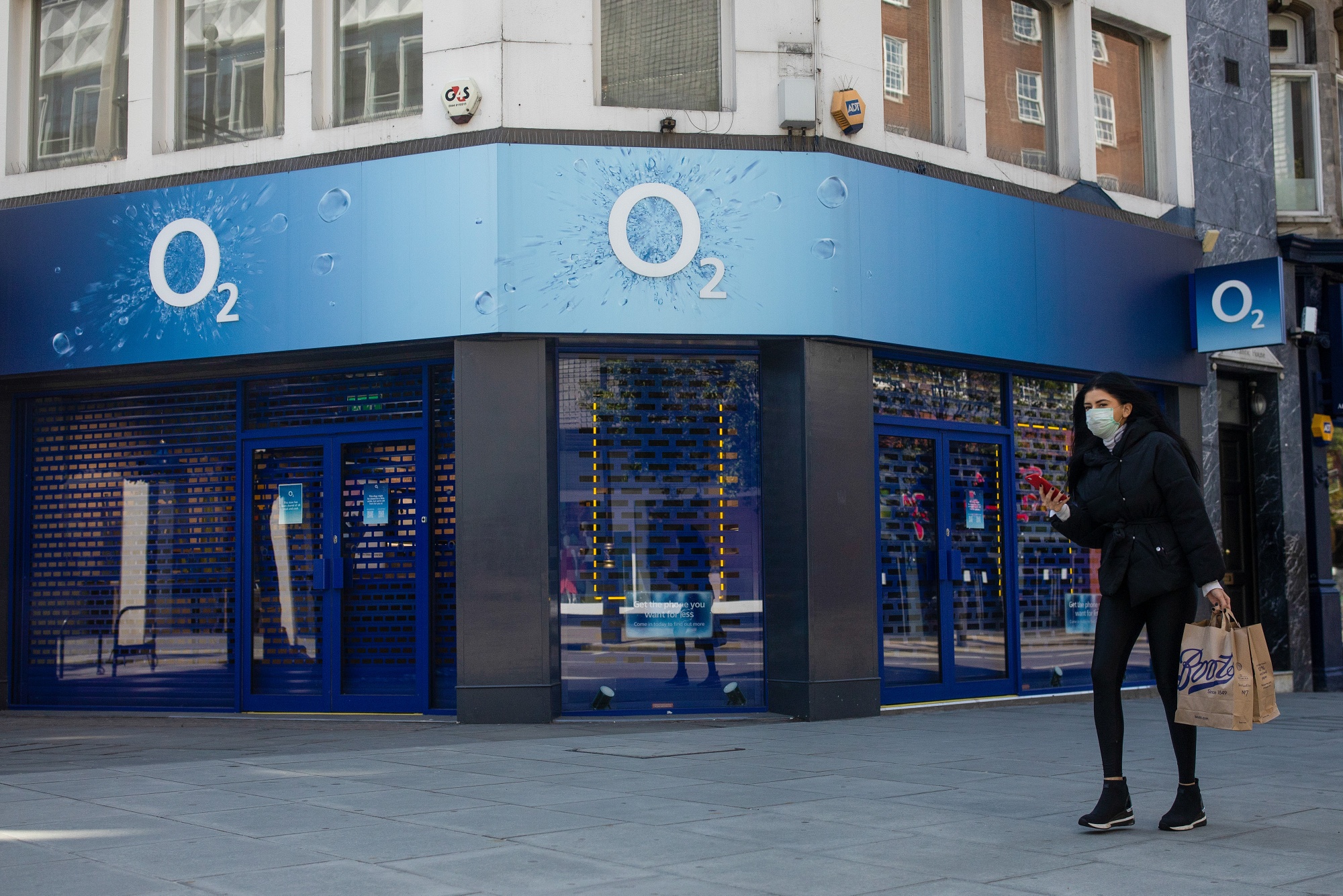 A pedestrian wearing a protective face mask passes an 02 store, a unit of Telfonica SA's U.K. unit, in London.