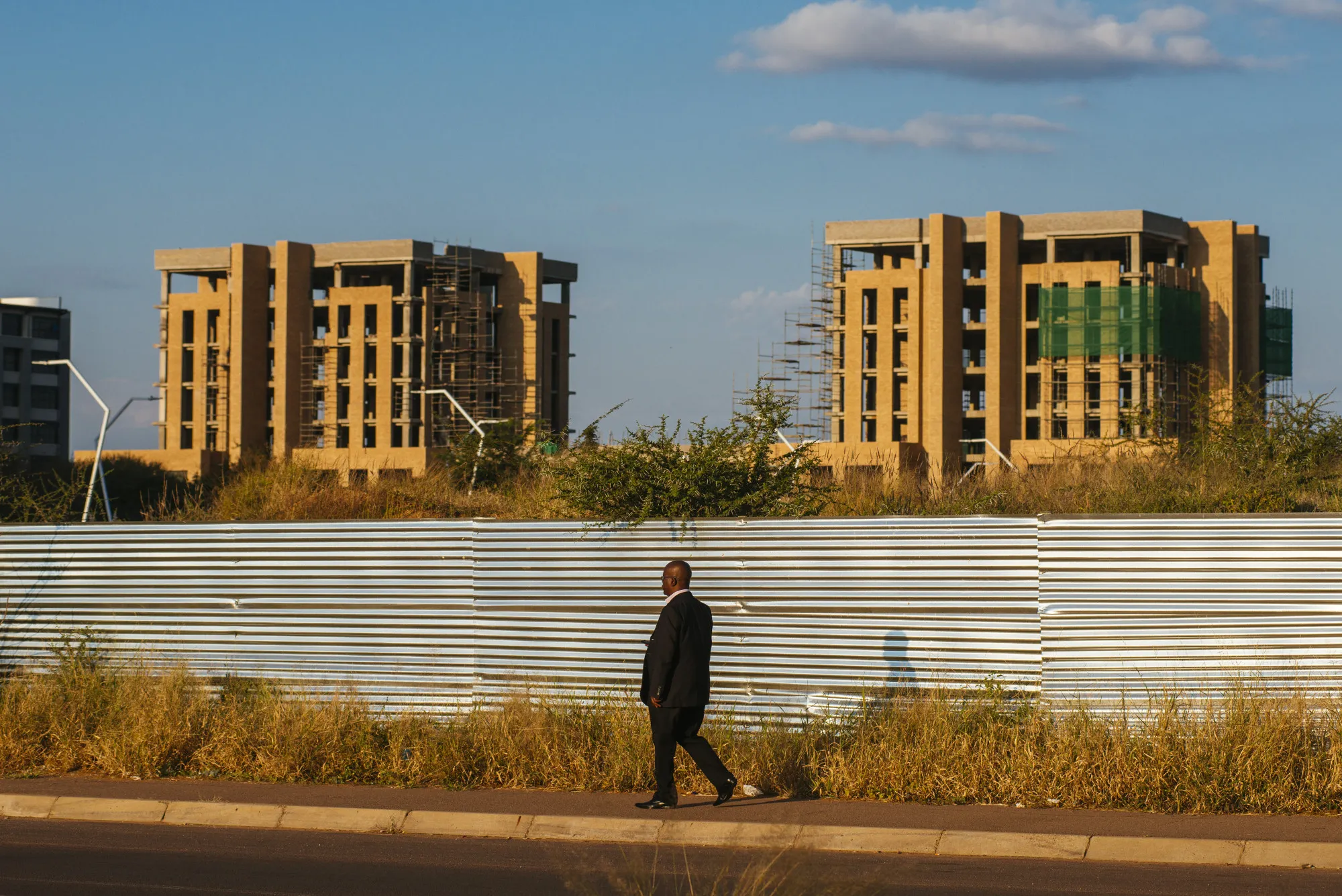 A pedestrian walks down the street as under-constructions buildings stand beyond in the central business district of Gaborone, Botswana.