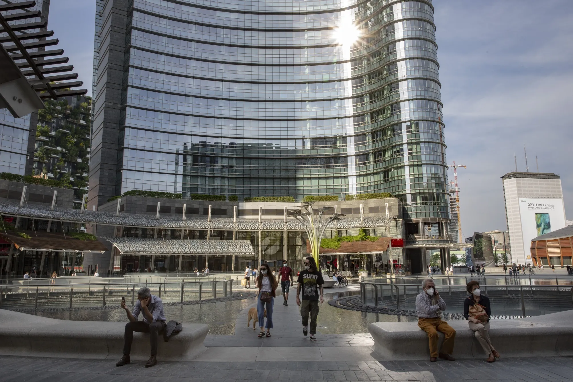 People wearing protective masks walk through Gae Aulenti square in Milan, on May 18.