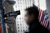 A pedestrian walks past the Wall Street street sign in front of the New York Stock Exchange (NYSE) in New York, U.S.