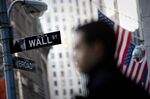 A pedestrian walks past the Wall Street street sign in front of the New York Stock Exchange (NYSE) in New York, U.S.
