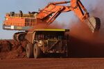 A digger loads ore onto a dump truck at a mine pit in the Pilbara region, Western Australia.
