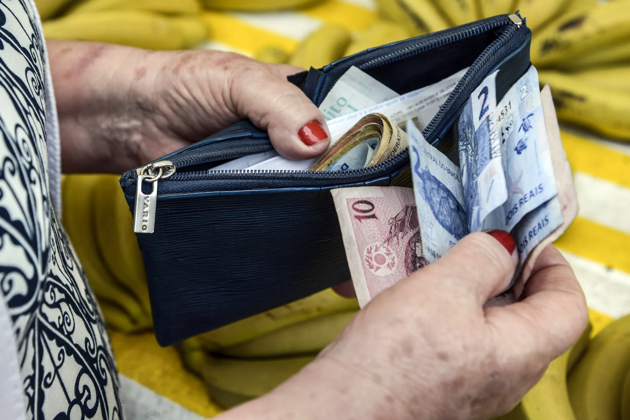 A shopper counts real banknotes before paying for fruit at a street market in Sao Paulo, Brazil.