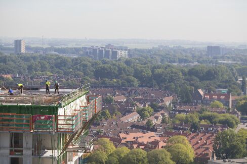 Construction workers stand on an upper floor of a new condominium in the Noord district