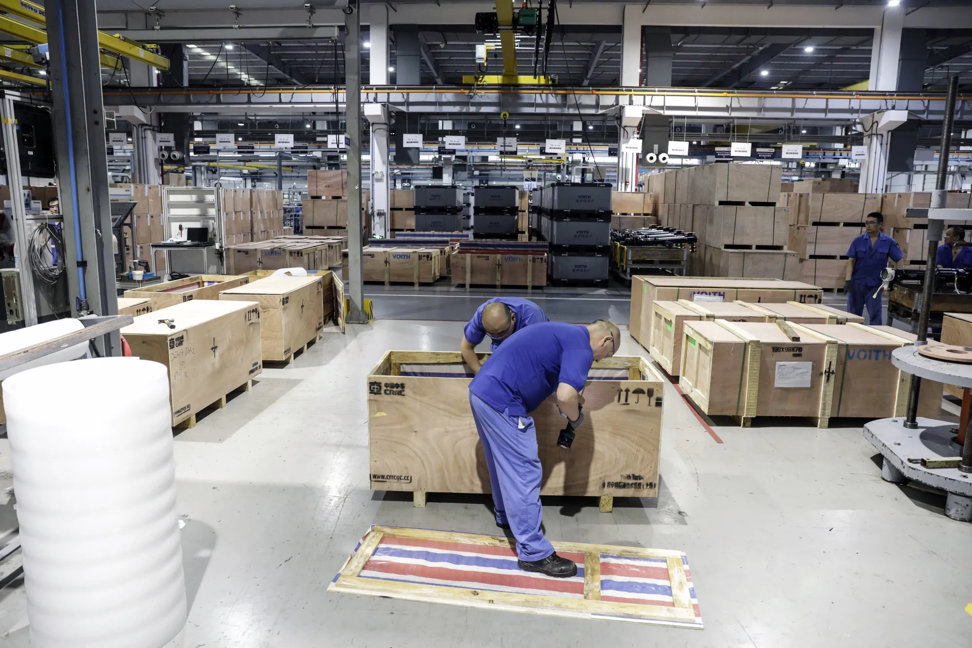 Employees work on the production floor at an auto parts factory in Shanghai, China.