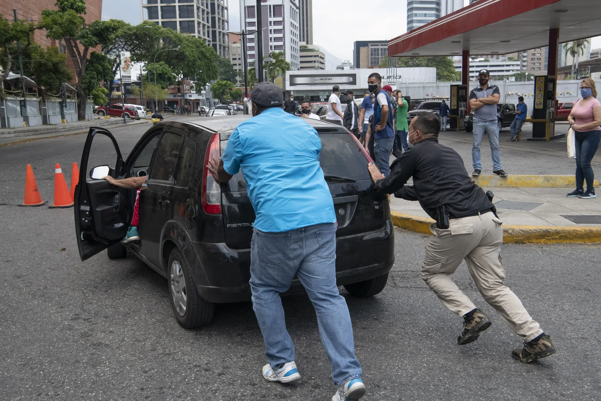 People push a vehicle that ran out of fuel to a PDVSA gas station in Caracas, Venezuela, on April 25.