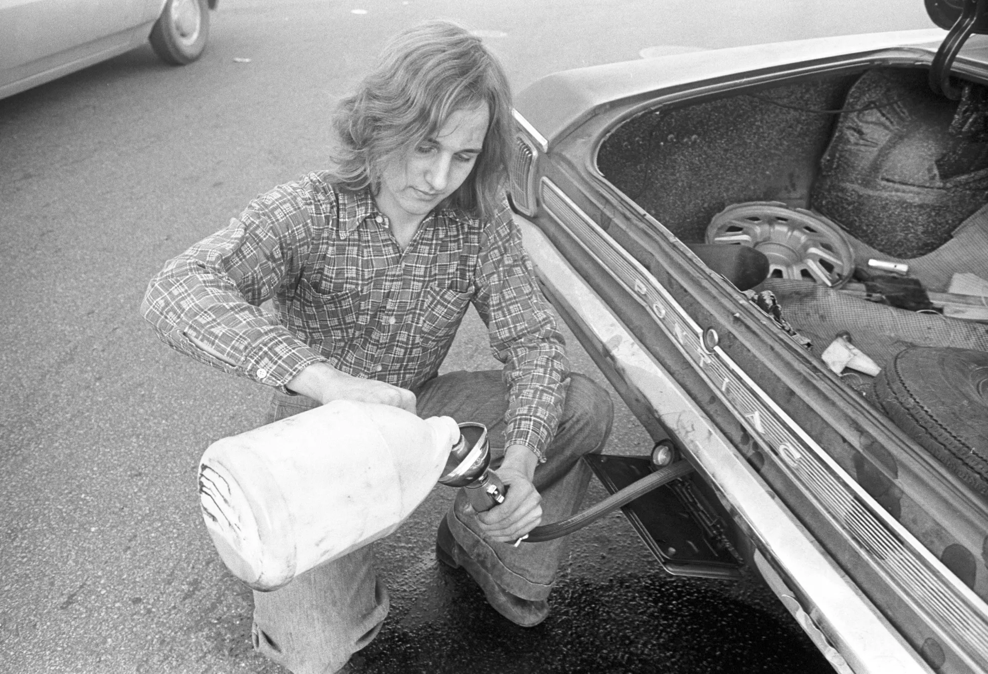 A motorist in Boston pours gas into a car from a jug during the oil crisis of 1973-74.
