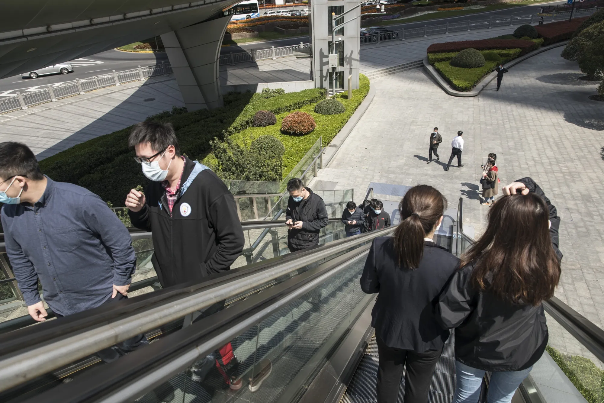 People wearing protective masks ride on escalators in the Lujiazui Financial District in Shanghai on March 20.