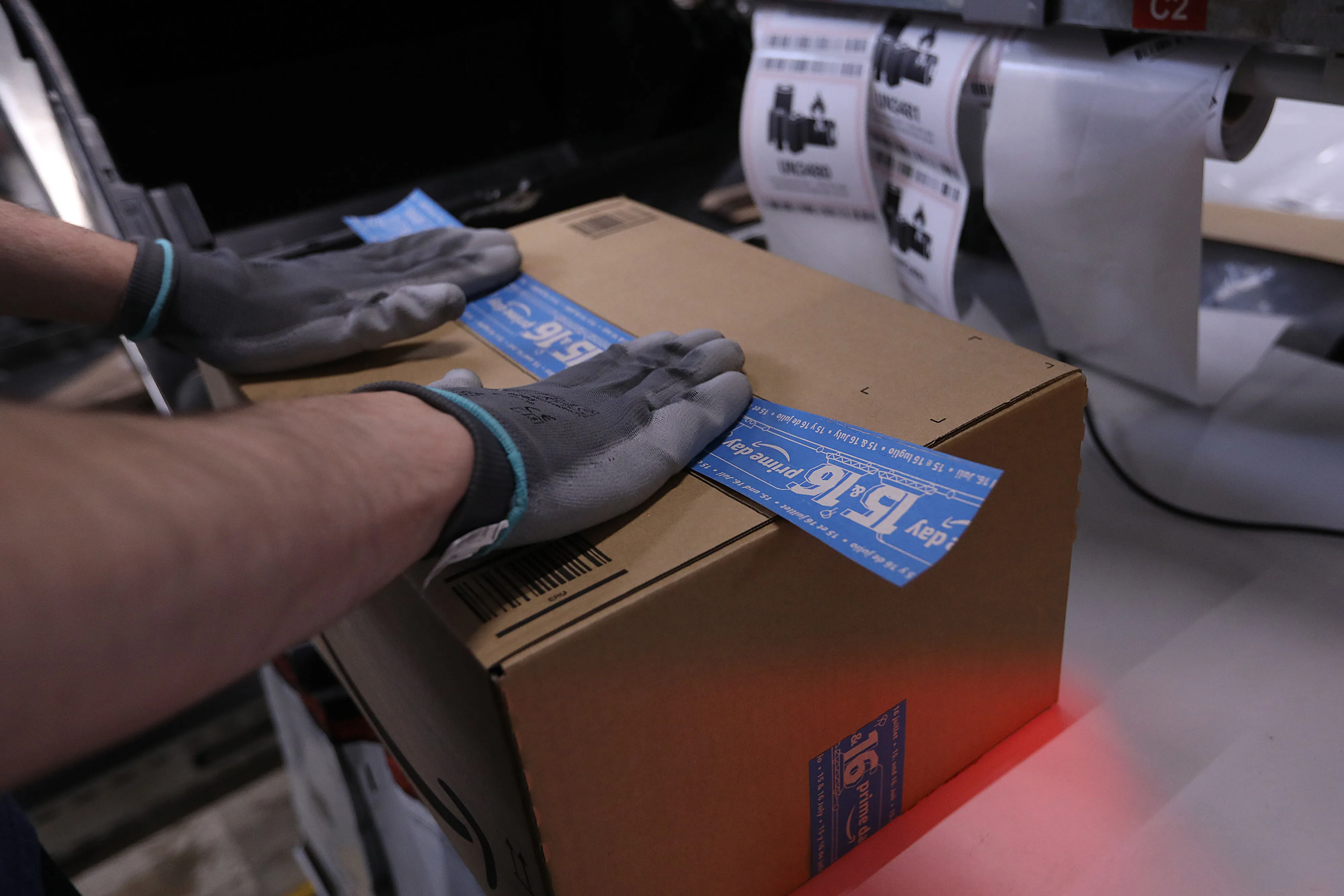An employee seals a box with Prime Day branded packing tape inside an Amazon.com&nbsp;fulfilment center during the online retailer's Prime Day sales promotion day in Koblenz, Germany.