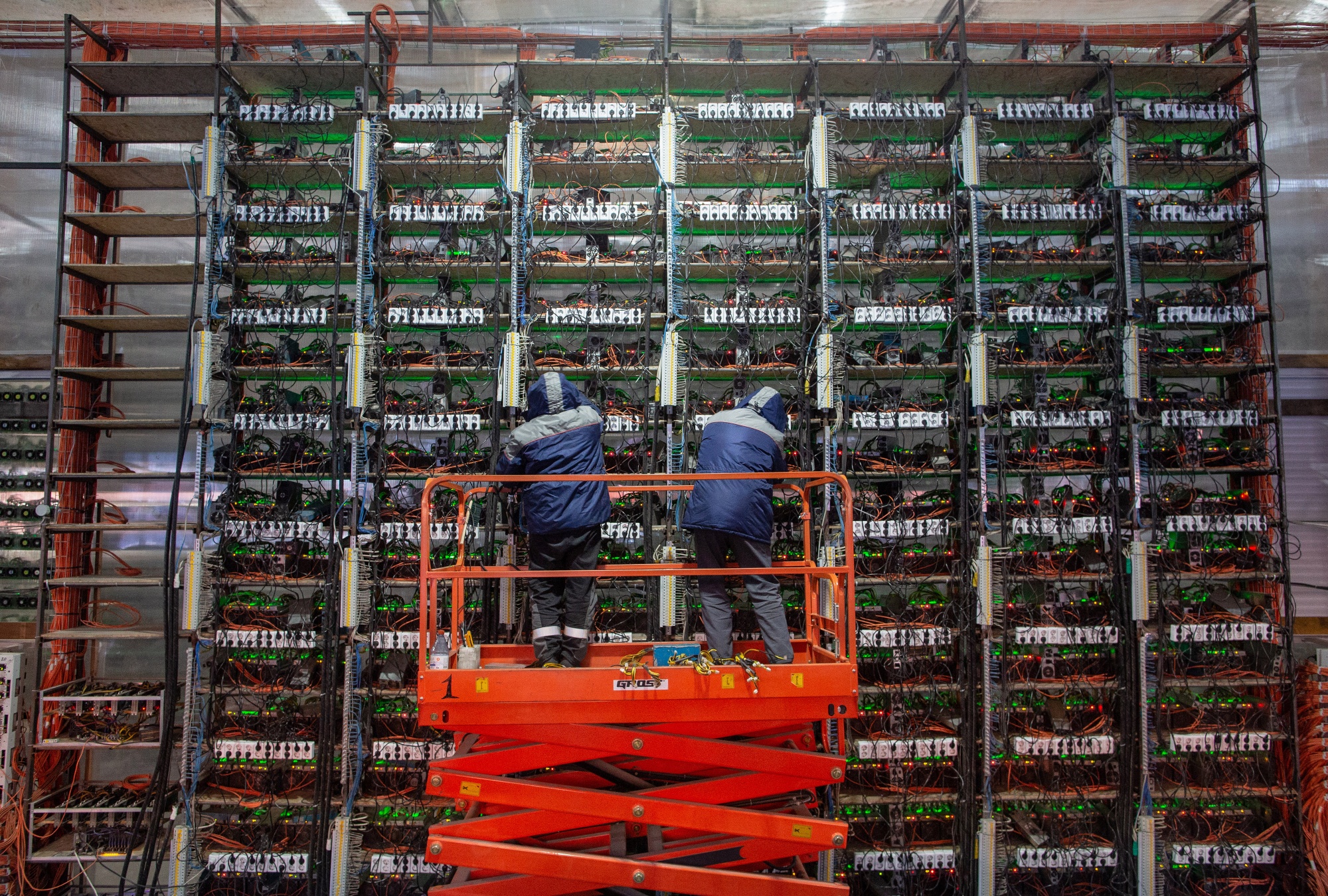 Engineers on a cherry picker adjust mining rigs at a cryptocurrency mining farm.&nbsp;