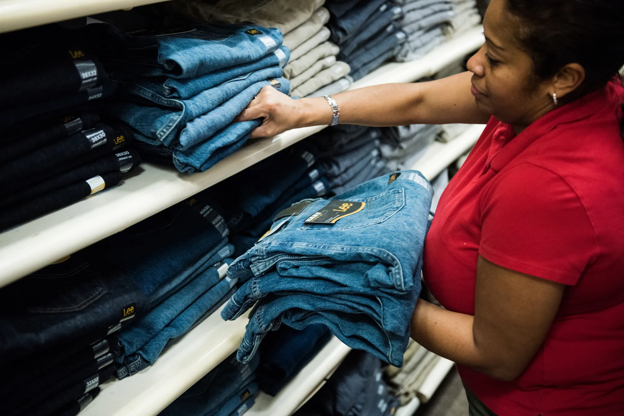 An employee restocks Lee brand jeans at a J.C. Penney Co. store in the Queens borough of New York, U.S.
