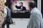 Pedestrians walk past a television screen broadcasting an image of North Korea Leader Kim Jong Un.