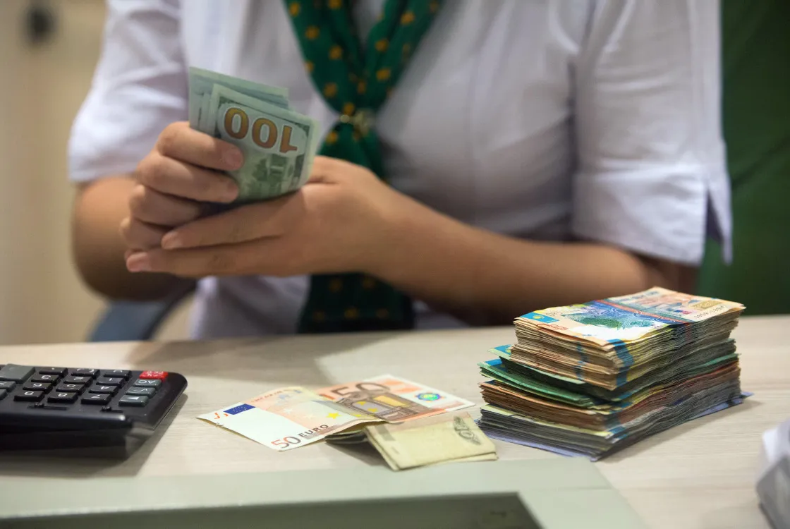 A cashier counts tenge banknotes.&nbsp;