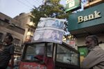A roadside money changer sits outside a Habib Bank Ltd. branch in Karachi, Pakistan.