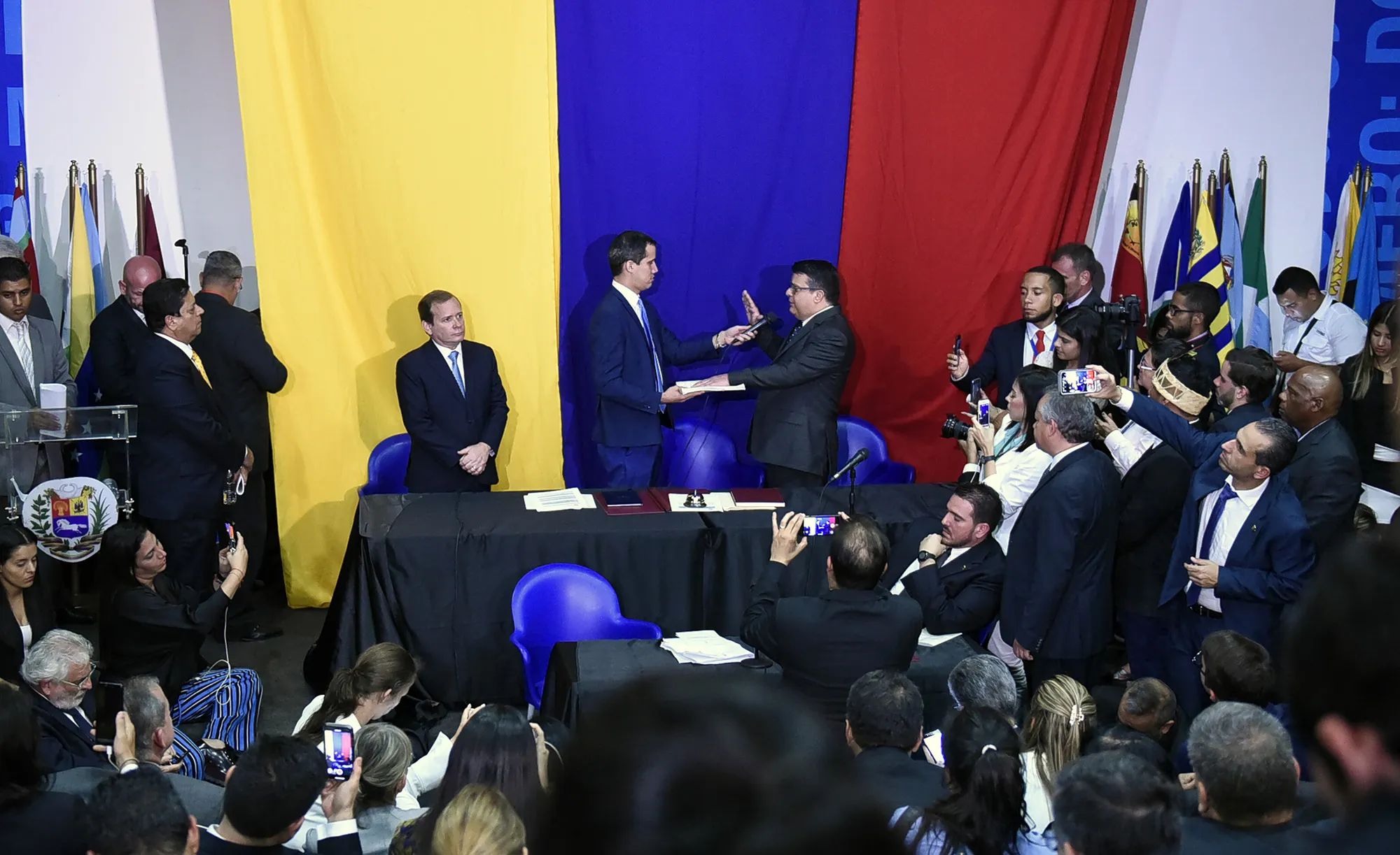 Juan Guaido, president of the National Assembly who swore himself in as the leader of Venezuela, center left, and lawmaker Juan Carlos Berrizbeitia, center right, attend an off-site session of congress for a second term swearing in ceremony at the auditorium of the El Nacional newspaper building in Caracas&nbsp;on&nbsp;Jan. 5, 2020.&nbsp;