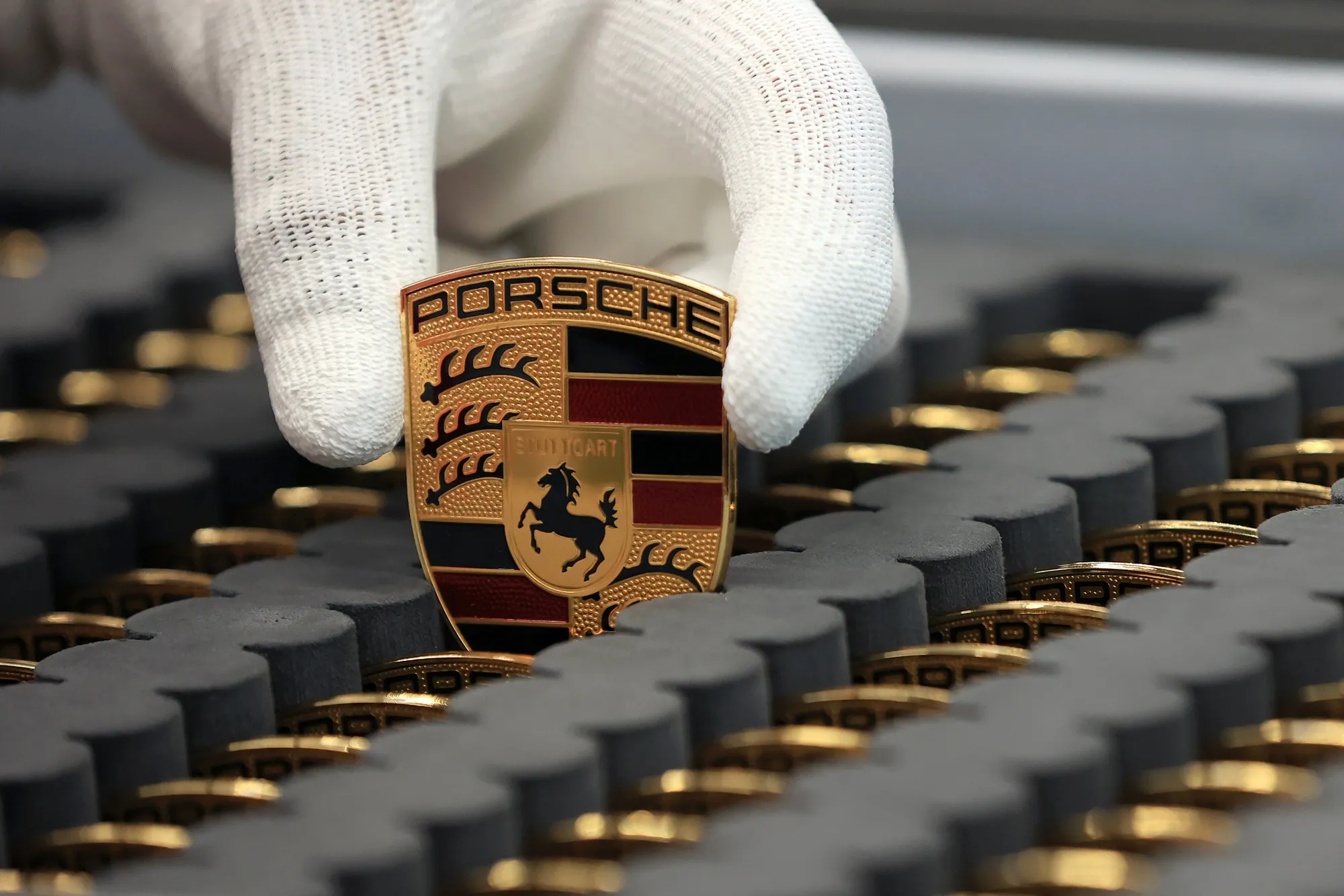 An employee selects a badge for an all-electric Porsche Taycan luxury automobile on the production line at the Porsche AG factory in Stuttgart.