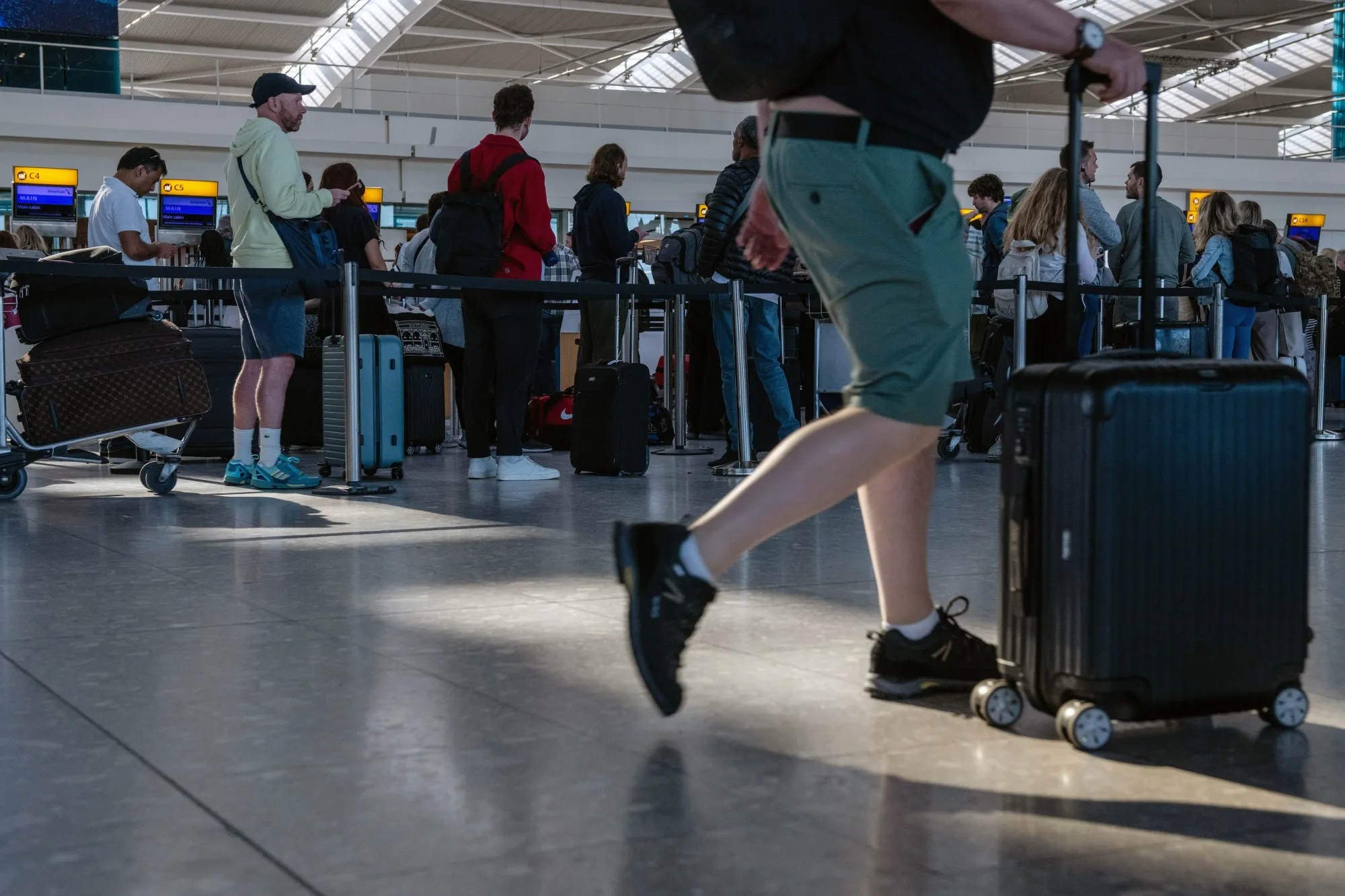 Passengers queue to check in at London Heathrow Airport.