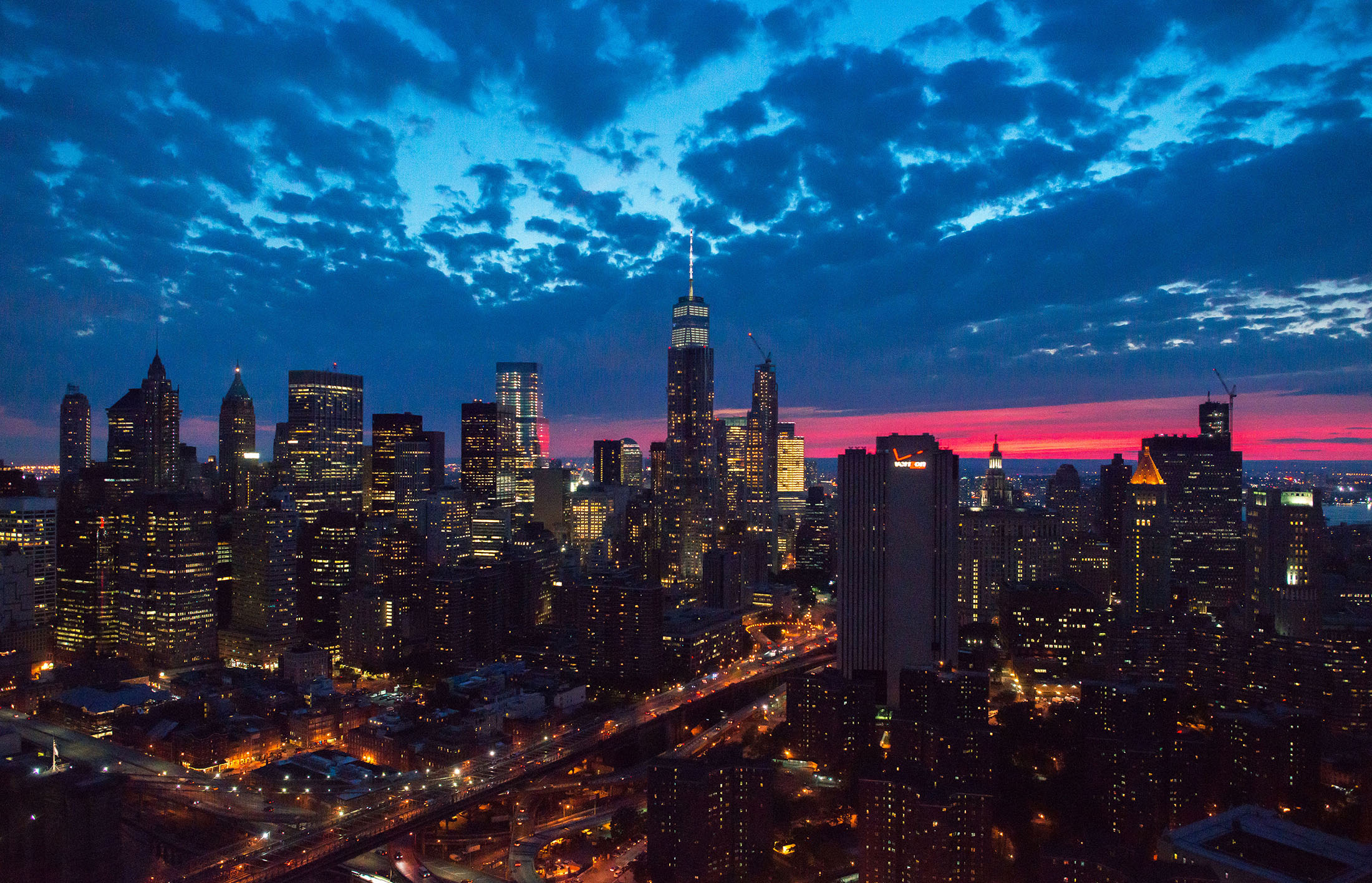 One World Trade Center stands the Lower Manhattan skyline at dusk in this aerial photograph.
