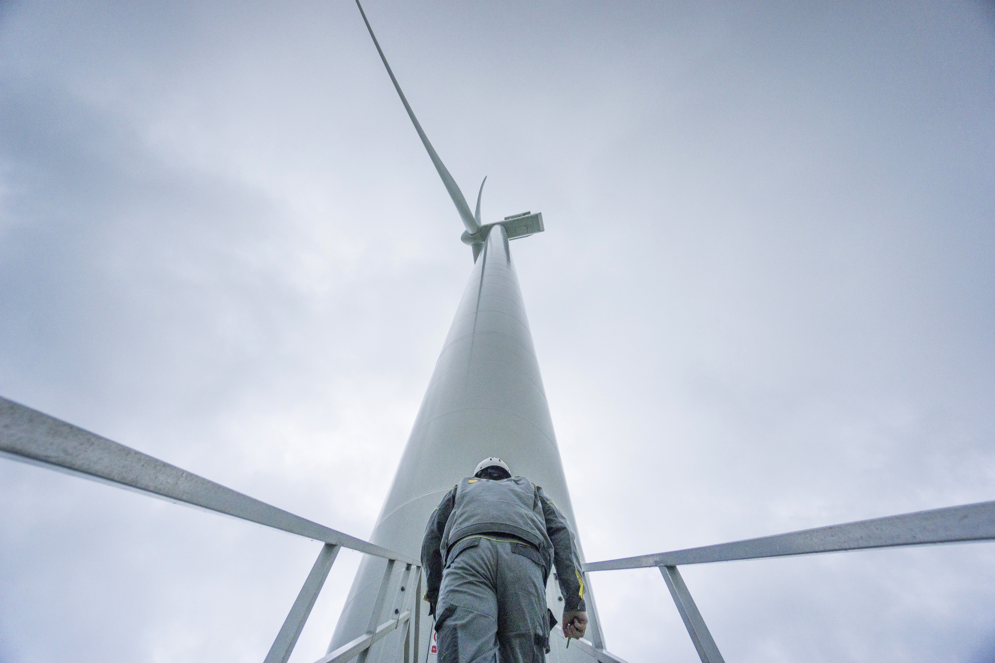 A worker climbs the access stairs to a Vestas Wind Systems A/S wind turbine at a windfarm in Botievo, Ukraine.