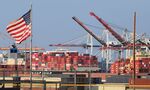 A US flag flies near containers stacked high on a cargo ship at the Port of Los Angeles,