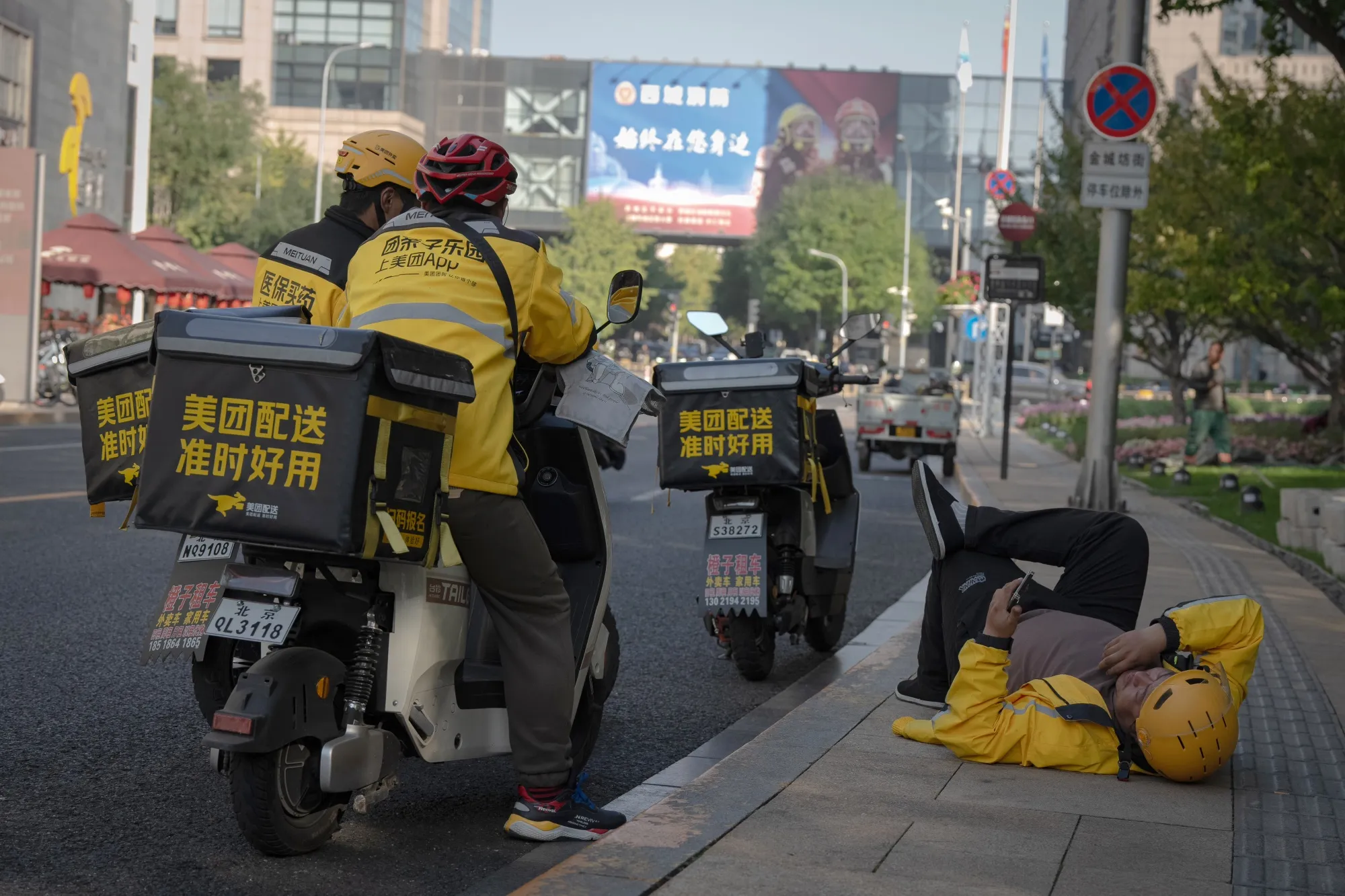 Food delivery couriers for Meituan wait for customers' orders in Beijing.